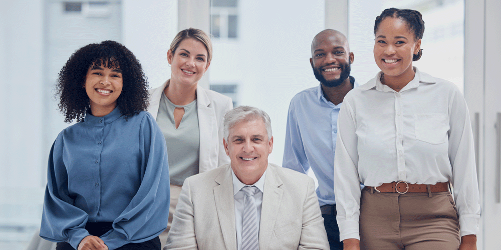 Smiling men and women in a business office in business attire.